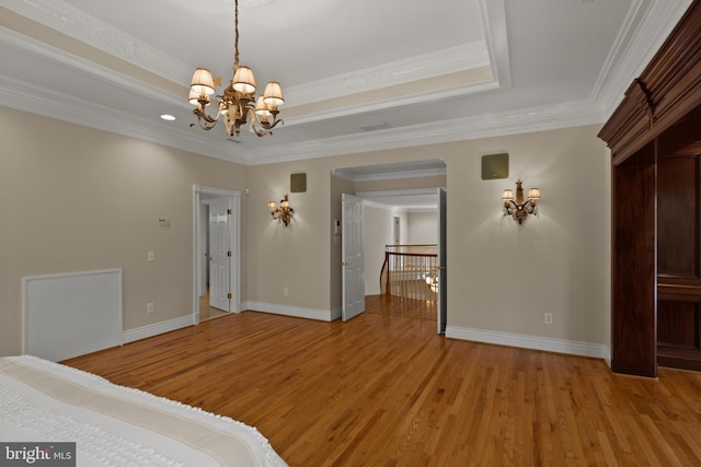 unfurnished bedroom with baseboards, a tray ceiling, an inviting chandelier, and light wood-style flooring