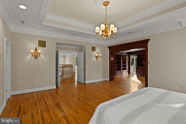 bedroom featuring a raised ceiling, a chandelier, light wood-style flooring, baseboards, and visible vents