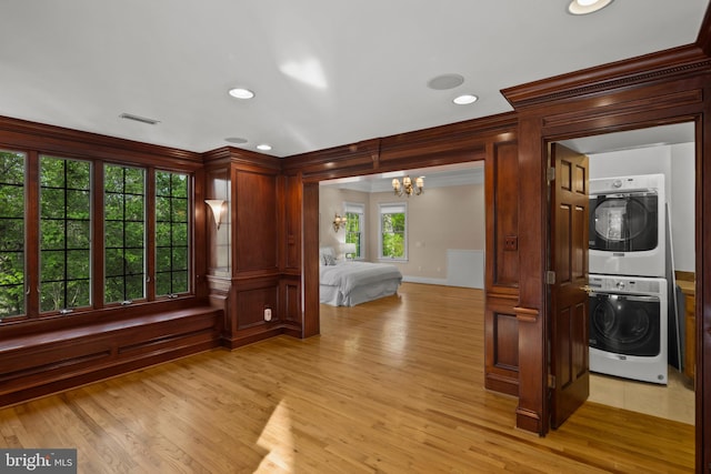 interior space with ornamental molding, stacked washer and dryer, light wood-style flooring, and visible vents