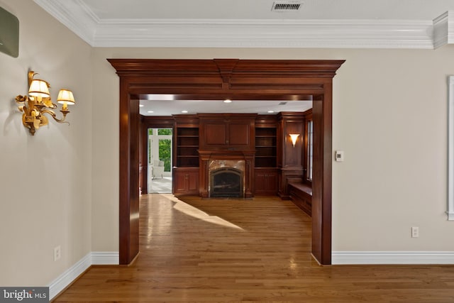 unfurnished living room featuring baseboards, ornamental molding, and wood finished floors