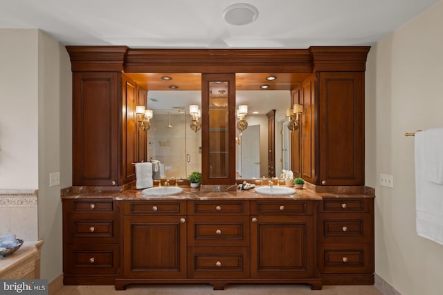 bathroom featuring double vanity, baseboards, a stall shower, and a sink