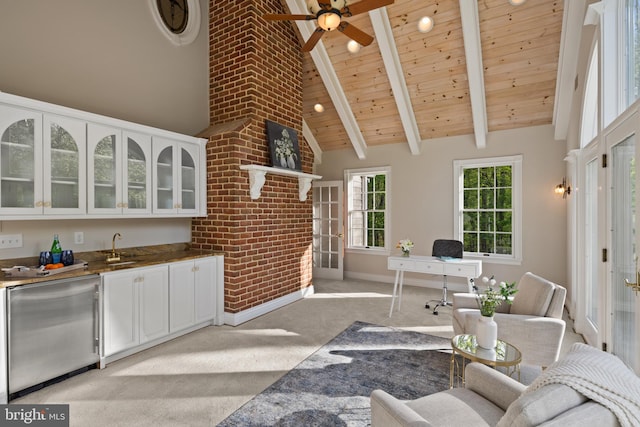 living area with ceiling fan, light carpet, beam ceiling, baseboards, and wood ceiling