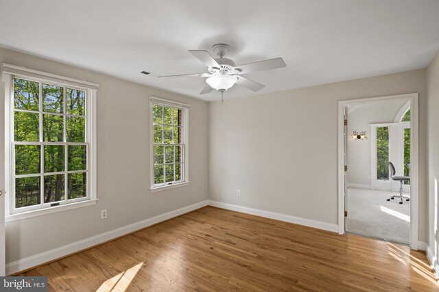 unfurnished room with baseboards, a ceiling fan, wood finished floors, and visible vents