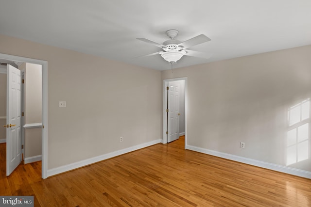 spare room featuring baseboards, a ceiling fan, and light wood-style flooring