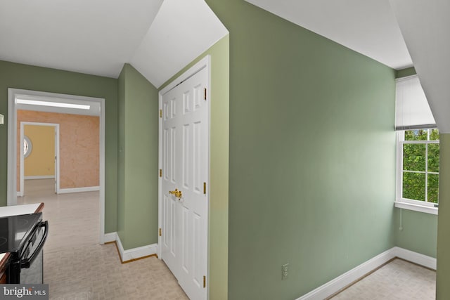 interior space with baseboards, lofted ceiling, and light floors