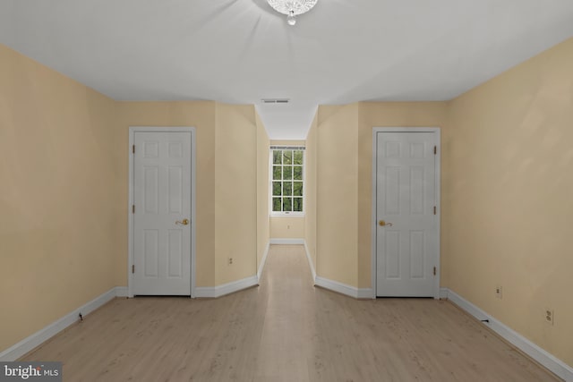 spare room featuring baseboards, wood finished floors, and visible vents