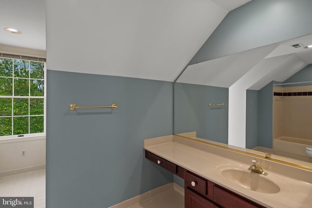 bathroom with baseboards, vaulted ceiling, and a wealth of natural light