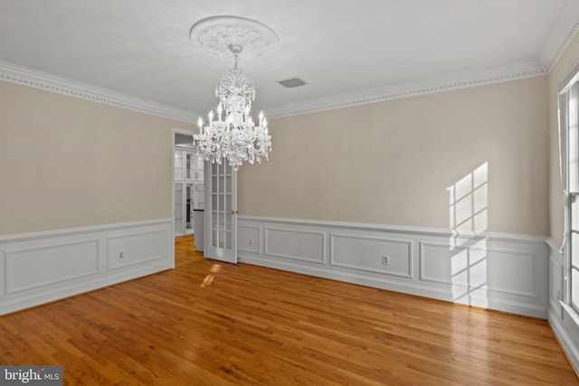 unfurnished dining area with crown molding, light wood finished floors, and a chandelier