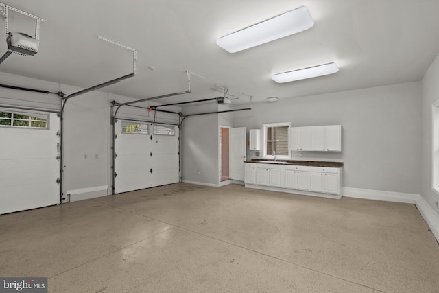garage featuring baseboards, a sink, and a garage door opener