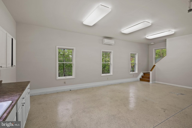 spare room with a sink, baseboards, a wall unit AC, and stairs
