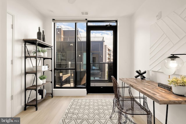 office with floor to ceiling windows, visible vents, baseboards, and wood finished floors