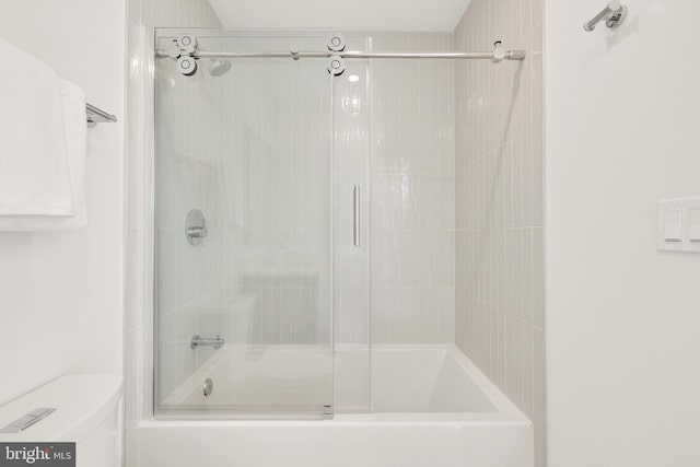 bathroom with toilet and combined bath / shower with glass door