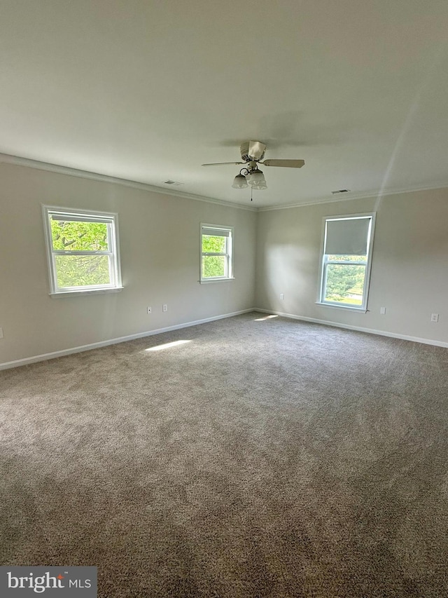 carpeted spare room featuring ornamental molding, a ceiling fan, and baseboards