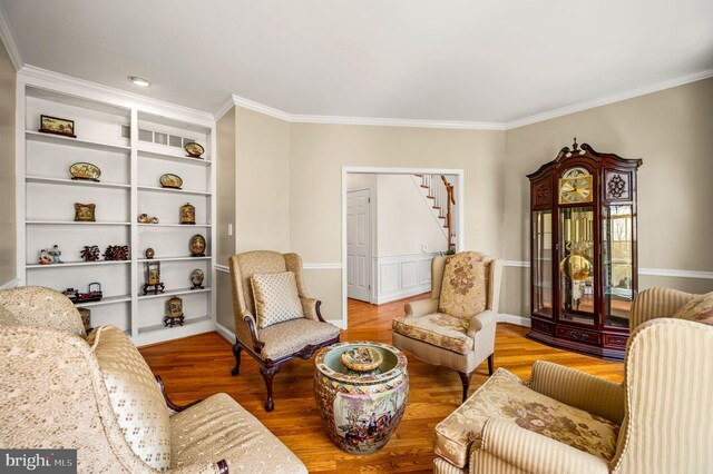 living area featuring wood finished floors, crown molding, baseboards, and stairs