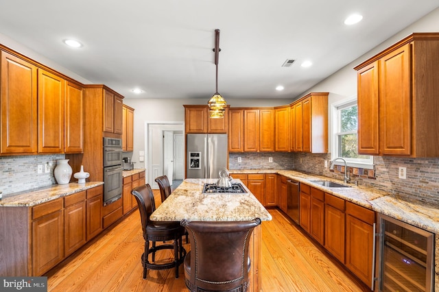 kitchen featuring beverage cooler, appliances with stainless steel finishes, backsplash, a sink, and a center island