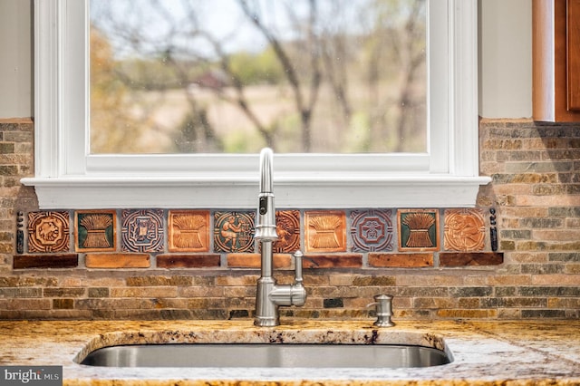 interior details with light stone counters, decorative backsplash, and a sink