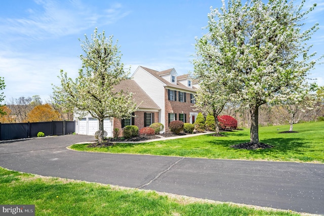 view of front of home with a front lawn, fence, driveway, and brick siding
