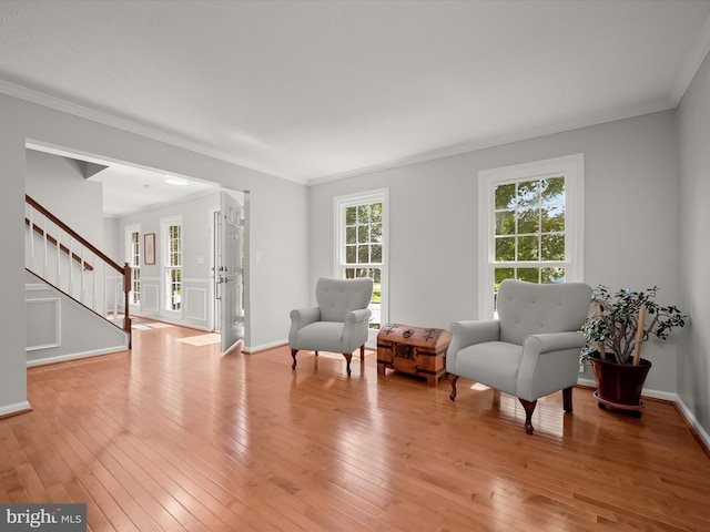 living area with stairway, light wood-type flooring, ornamental molding, and baseboards