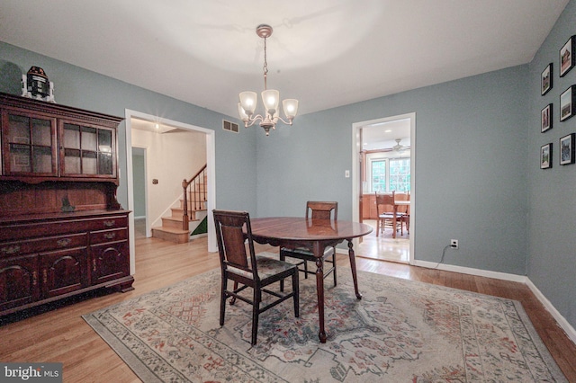 dining area with a notable chandelier, stairway, visible vents, and light wood-type flooring