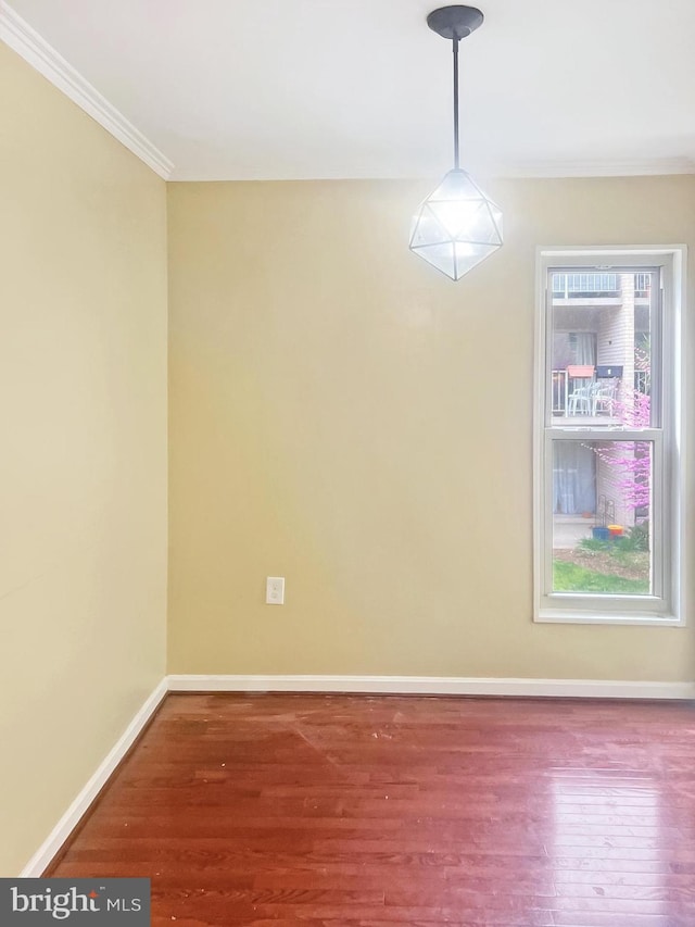 empty room featuring ornamental molding, baseboards, and wood finished floors