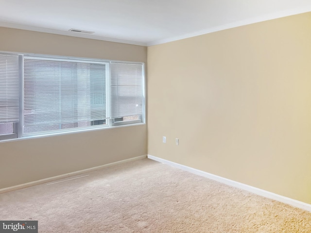 carpeted spare room featuring baseboards and crown molding