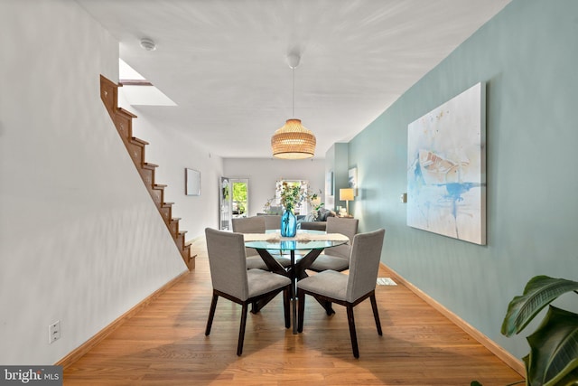 dining area with light wood-style flooring, baseboards, and stairs