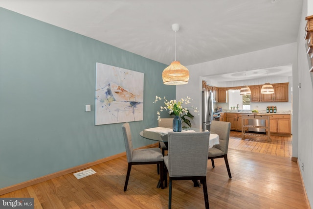 dining space featuring light wood-style floors and baseboards