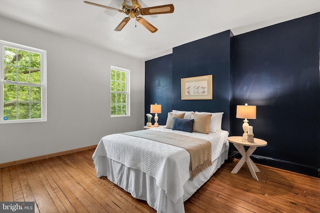 bedroom with hardwood / wood-style flooring, baseboards, multiple windows, and a ceiling fan