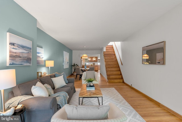 living area with stairs, light wood-style flooring, and baseboards