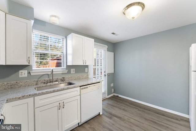 kitchen featuring light wood finished floors, visible vents, a sink, white appliances, and white cabinetry