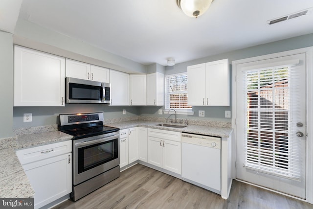 kitchen with white cabinets, visible vents, stainless steel appliances, and a sink