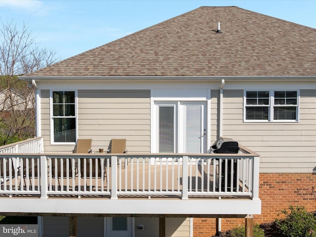 back of house with roof with shingles and a deck