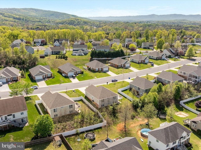drone / aerial view featuring a wooded view, a mountain view, and a residential view