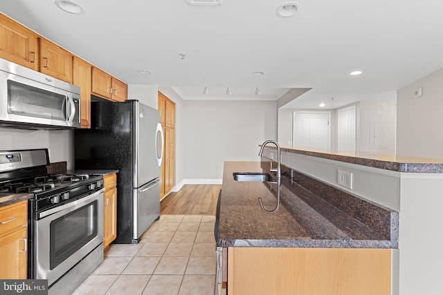 kitchen with light tile patterned floors, a sink, appliances with stainless steel finishes, an island with sink, and recessed lighting