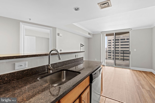 kitchen featuring light wood-type flooring, crown molding, visible vents, stainless steel dishwasher, and a sink