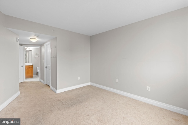 unfurnished room with light colored carpet and baseboards