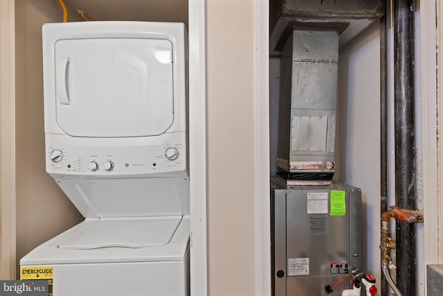laundry area with heating unit, stacked washer / dryer, and laundry area