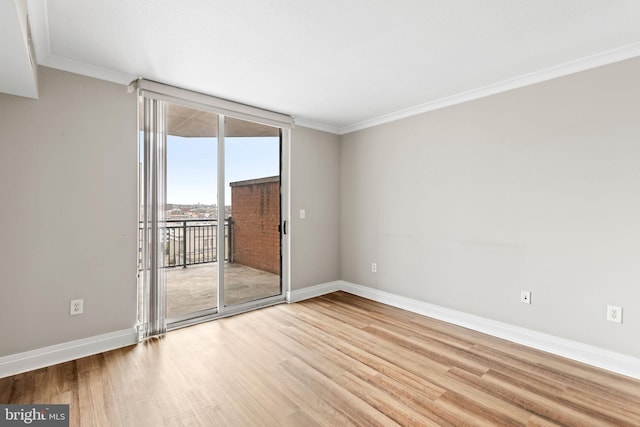 empty room featuring light wood-style floors, baseboards, and crown molding
