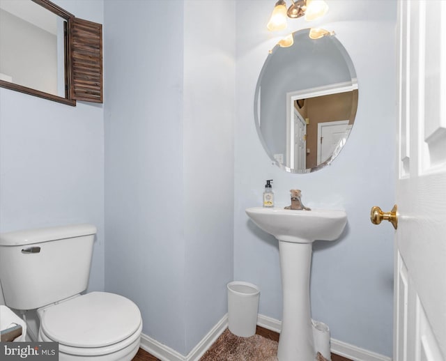 bathroom featuring baseboards, toilet, and a sink