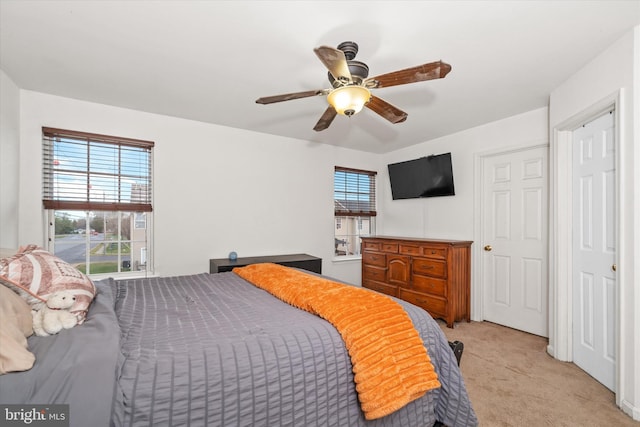 bedroom featuring light carpet, multiple windows, and ceiling fan