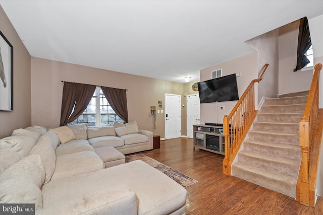 living area featuring visible vents, stairway, and wood finished floors
