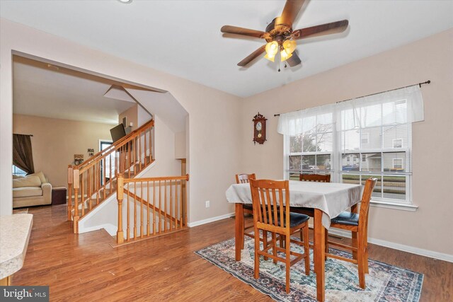 dining space featuring baseboards, wood finished floors, stairway, and a ceiling fan