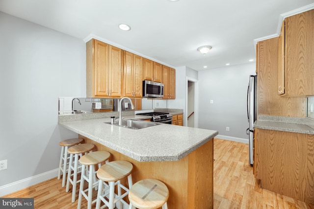 kitchen with a peninsula, light wood-style floors, a sink, and stainless steel appliances