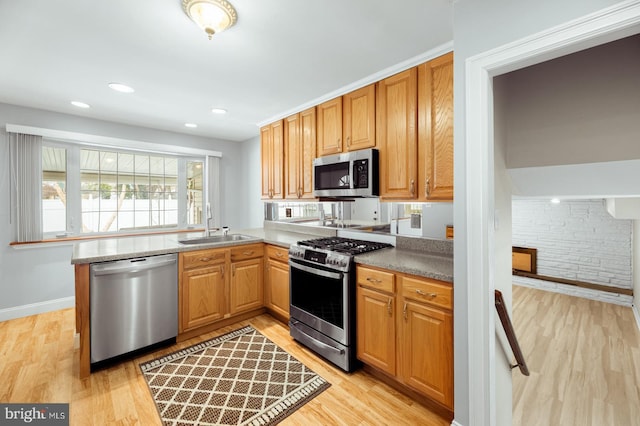 kitchen with baseboards, stainless steel appliances, recessed lighting, a sink, and light wood-type flooring
