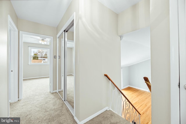 hall featuring baseboards, carpet floors, and an upstairs landing