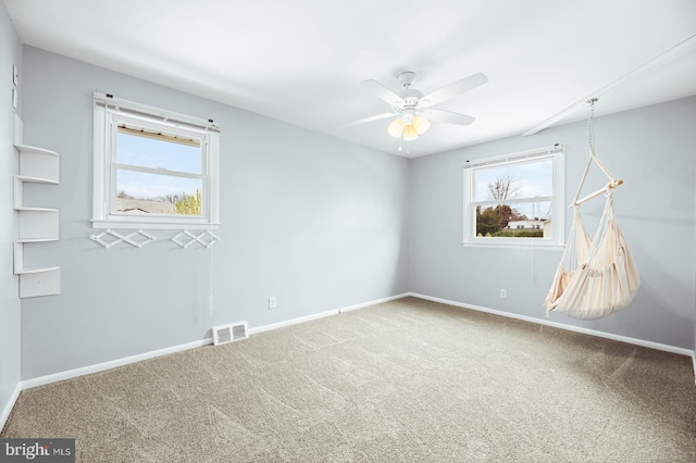 carpeted spare room with a ceiling fan, baseboards, and visible vents