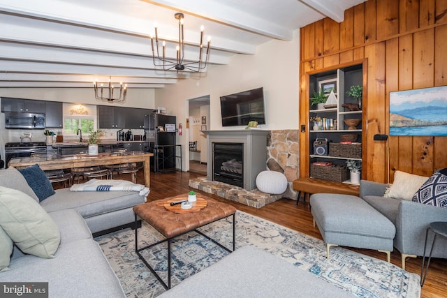 16 Jrs Dr, Mc Henry, MD 21541 - living area featuring wood walls, wood finished floors, beam ceiling, a chandelier, and a glass covered fireplace