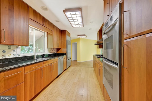 1408 Margarette Ave, Baltimore, MD 21286 - kitchen featuring stainless steel appliances, backsplash, dark stone countertops, and light wood-style flooring