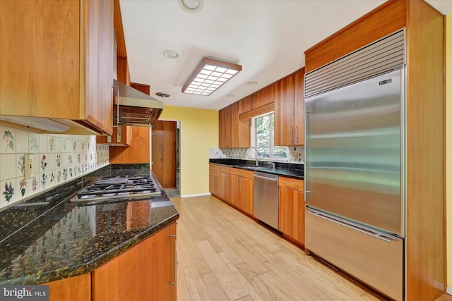 1408 Margarette Ave, Baltimore, MD 21286 - kitchen featuring appliances with stainless steel finishes, range hood, decorative backsplash, light wood-style flooring, and brown cabinetry