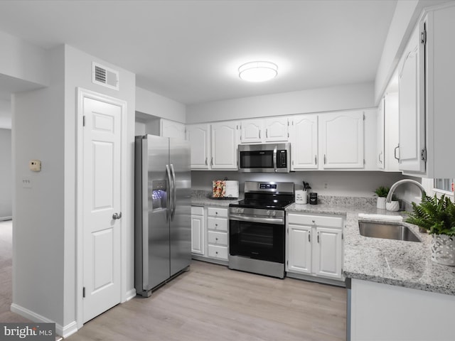 12617 Monarch Ct, Woodbridge, VA 22192 - kitchen with stainless steel appliances, a sink, white cabinetry, and light stone countertops